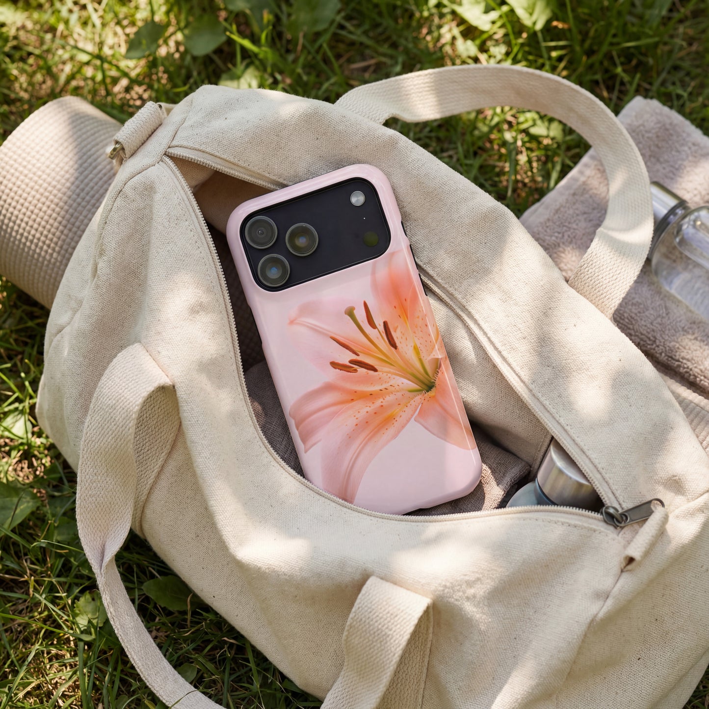 iPhone 17 pro max case with a pink floral design sitting in a beige yoga bag on grass