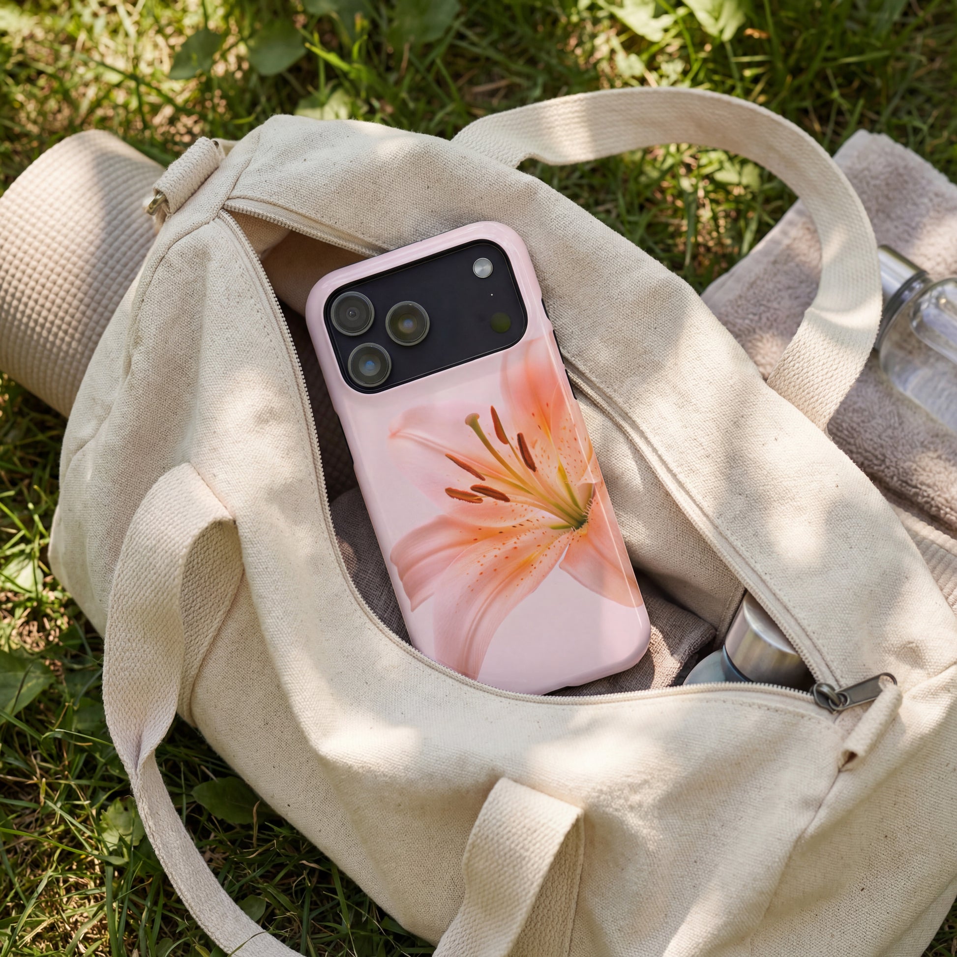 iPhone 17 pro max case with a pink floral design sitting in a beige yoga bag on grass