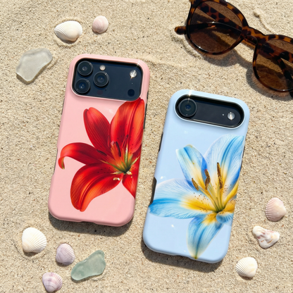 Two floral iphone cases sitting on sand with shells and sunglasses