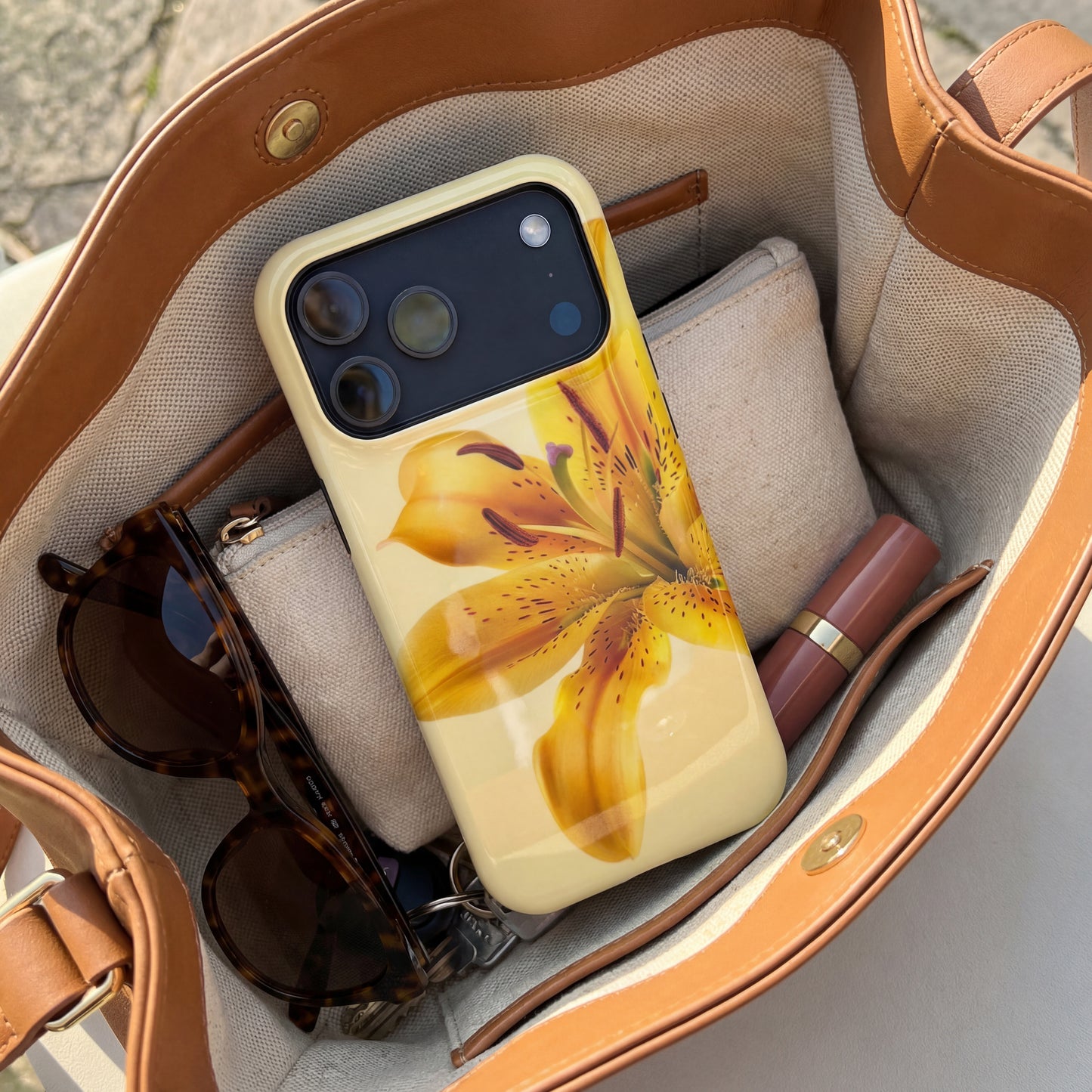 iPhone 17 pro max case with a yellow floral design sitting inside a handbag