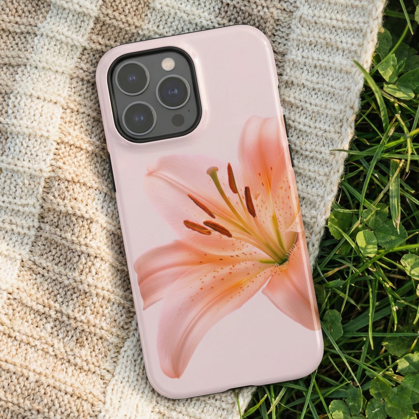 iPhone case with a pink lily design on a textured fabric and grass background