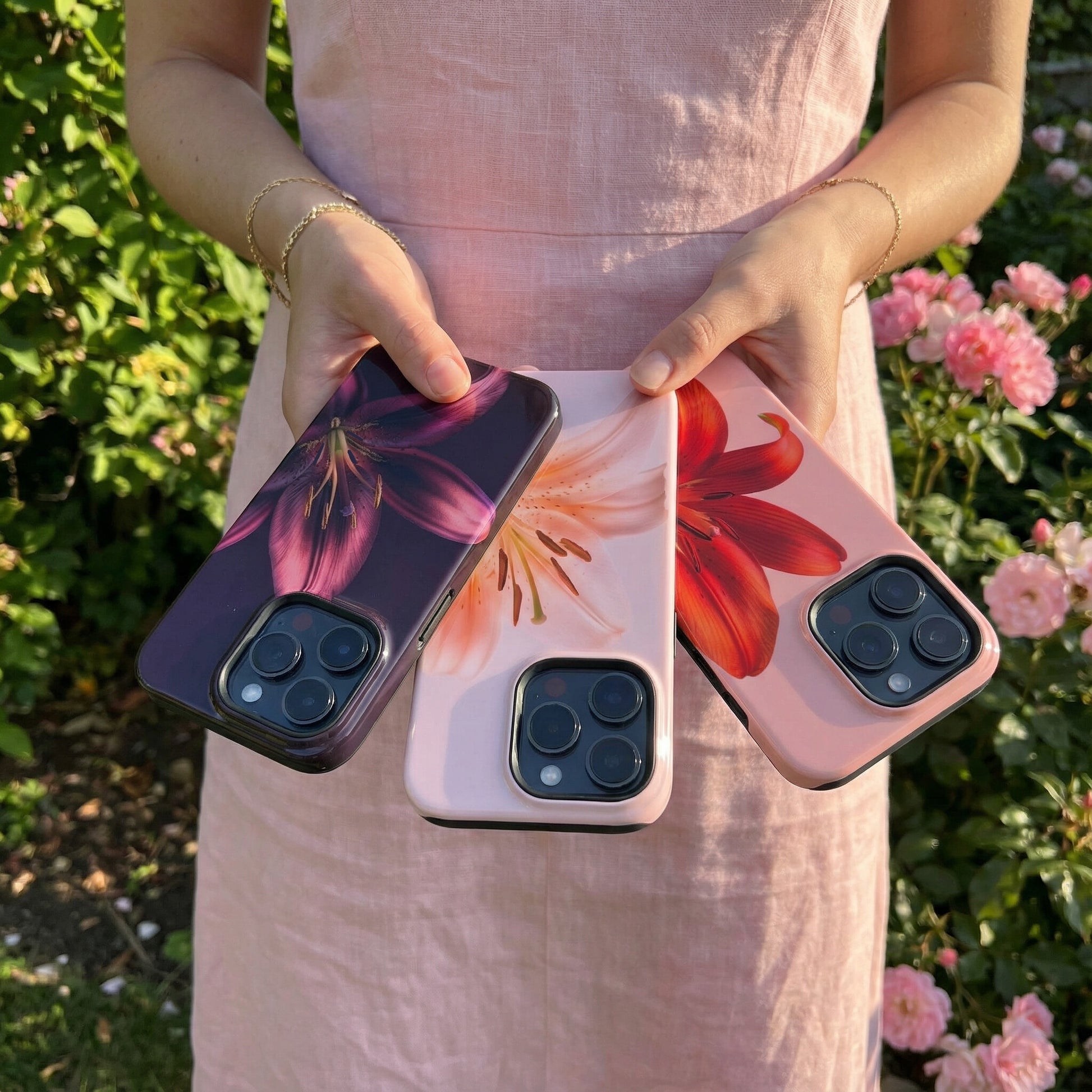 Woman holding three floral iphone cases with a garden background