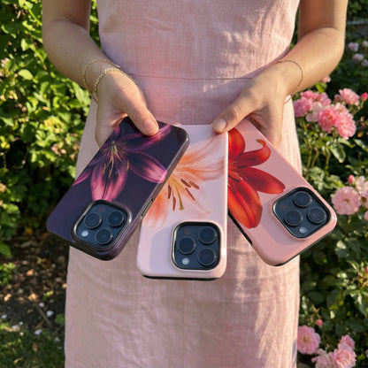 Woman holding three floral iphone cases with a garden background