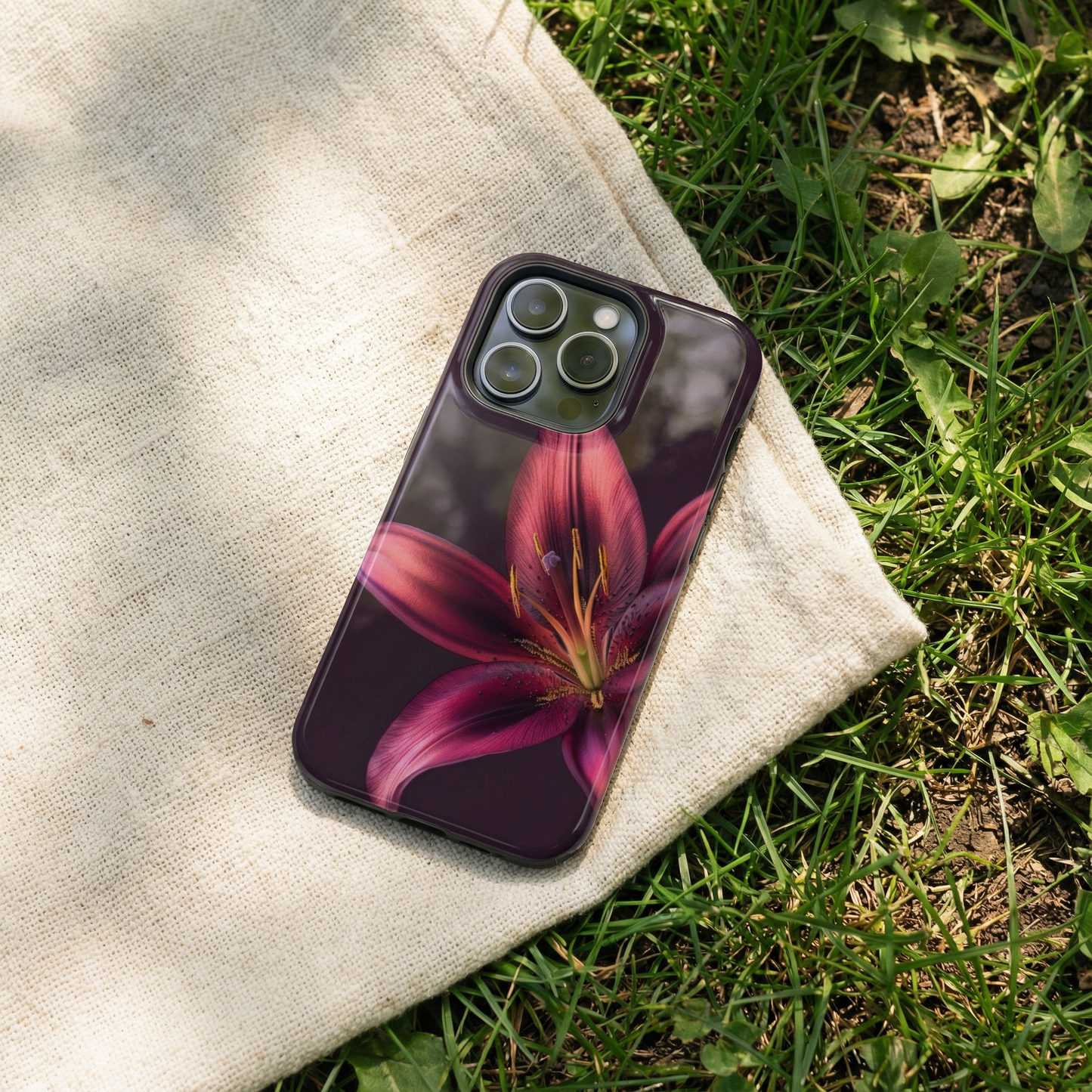 iPhone case with purple floral design sitting on a fabric surface outdoors