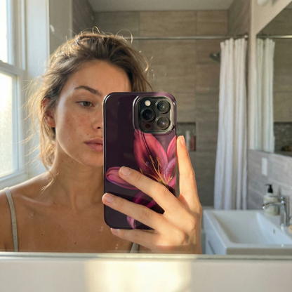 Woman holding an iphone with a floral case in front of a mirror in a bathroom taking a selfie.