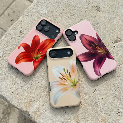 Three iphone cases with floral designs sitting on a stone surface