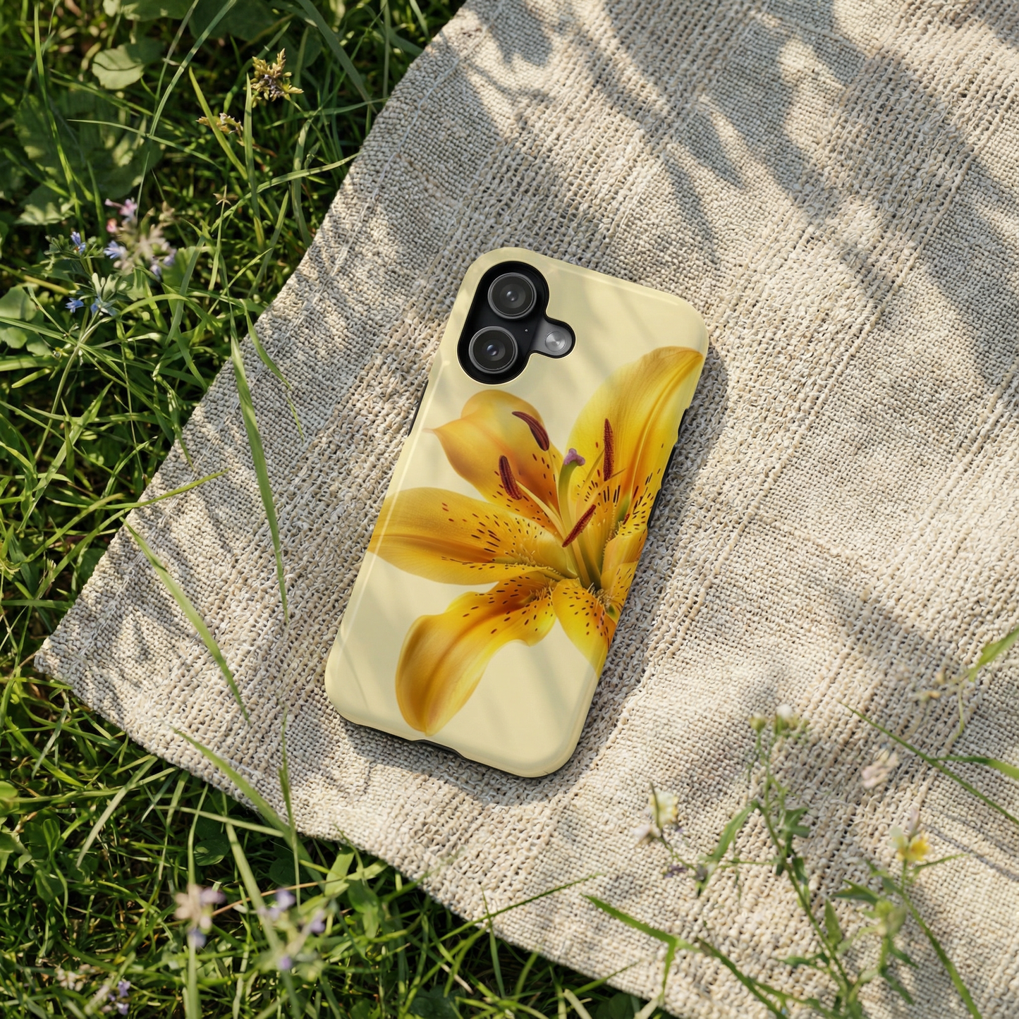 iPhone 17 case with a yellow flower design on a textured surface with grass in the background