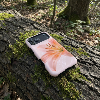 iPhone 17 pro max case with a pink floral design sitting on a tree trunk in a forest setting