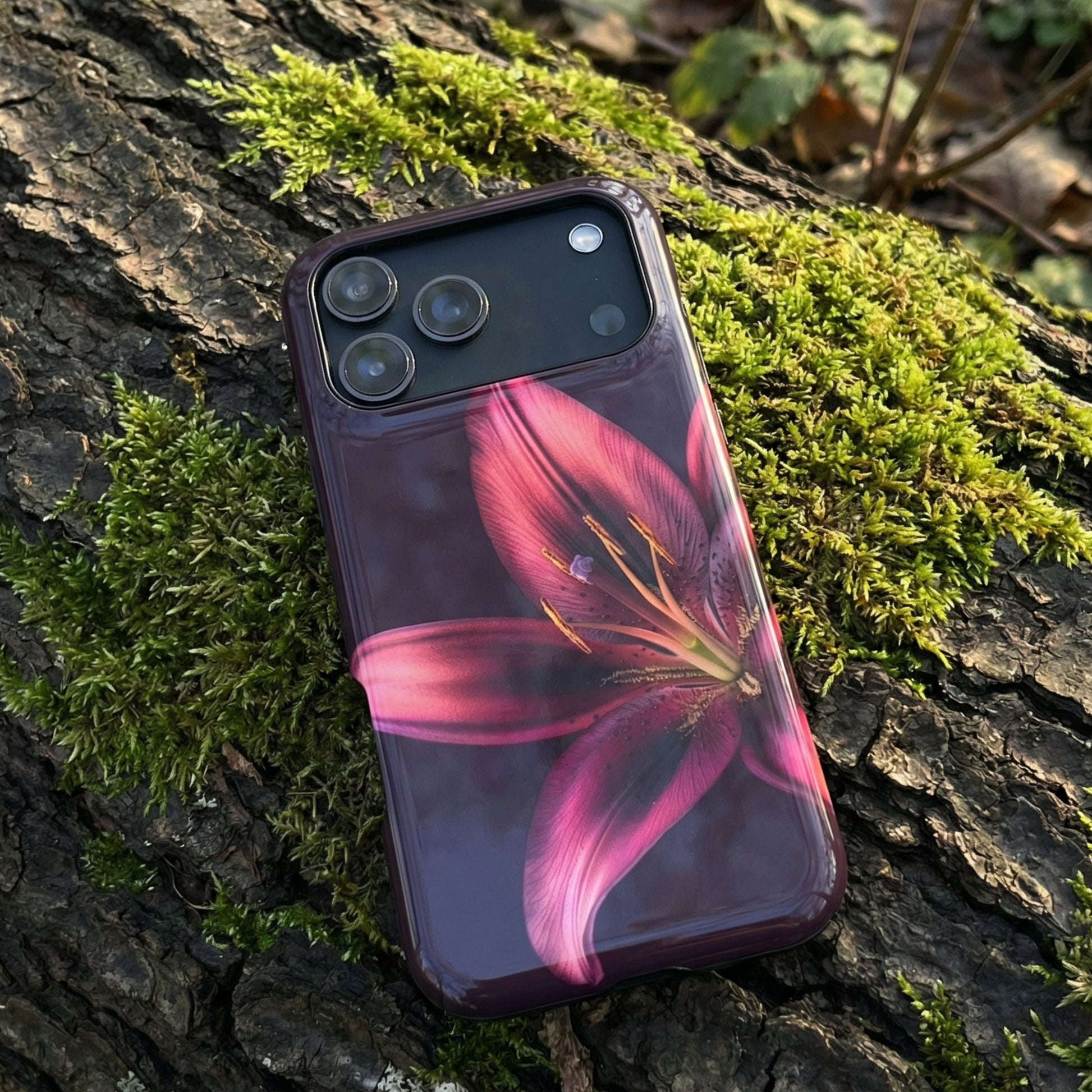 iPhone 17 pro max case with a purple floral design sitting on a mossy tree trunk