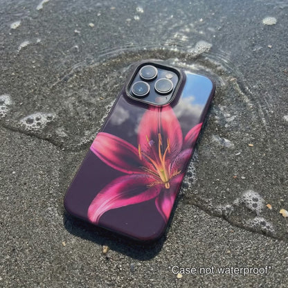 purple iPhone case with floral design sitting on beach sand as waves gentle wash over it.