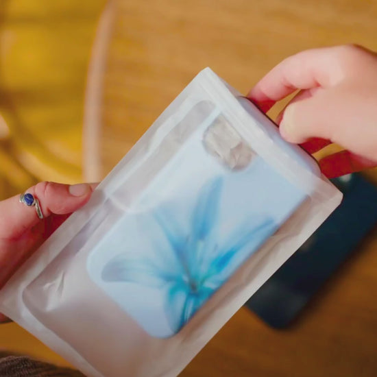 unboxing video of a Floral iPhone case with a blue lily flower on a soft blue background being taken out of its delivery pouch. 