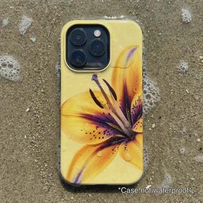 yellow iPhone case with floral design sitting on beach sand as waves gentle wash over it.