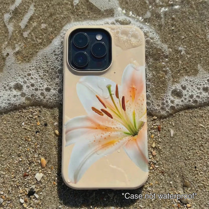 cream iPhone case with white floral design sitting on beach sand as waves gentle wash over it.